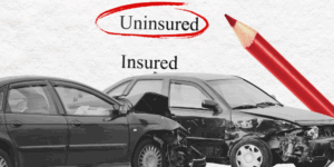 Collage-type image featuring a black-and-white car wreck in front of a piece of paper with the words "Uninsured" and "Insured." Uninsured is circled in red, and a red pencil is nearby on the page, layered behind the cars.
