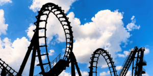 An ominous, fully-blacked out rollercoaster outline is seen against a bright blue sky. The stark contrast represents the complexity and emotional toll of amusement park ride injury cases.