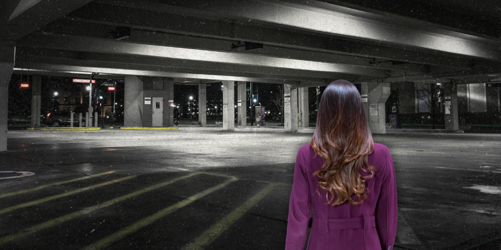 view from behind a woman looking forward into a dark parking garage